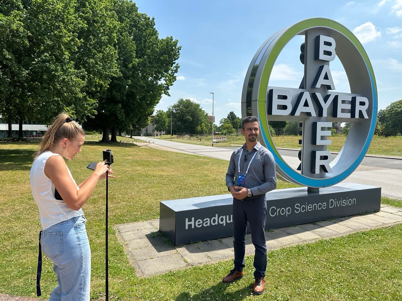 DynamoBot team member being filmed next to the Bayer Crop Science Division headquarters sign.