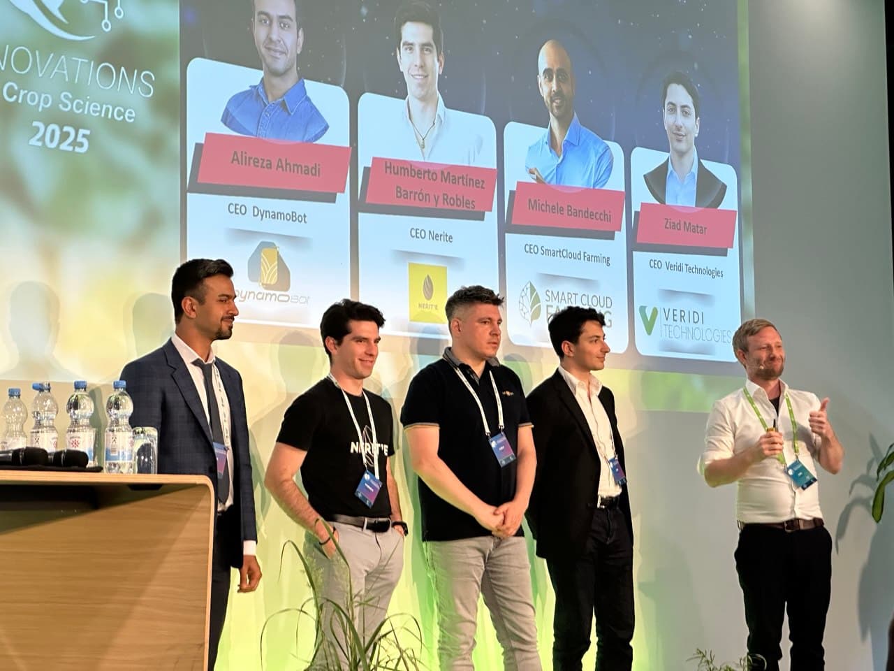 Five founders on stage at a Crop Science 2025 innovation event, with DynamoBot CEO Alireza Ahmadi named on screen.