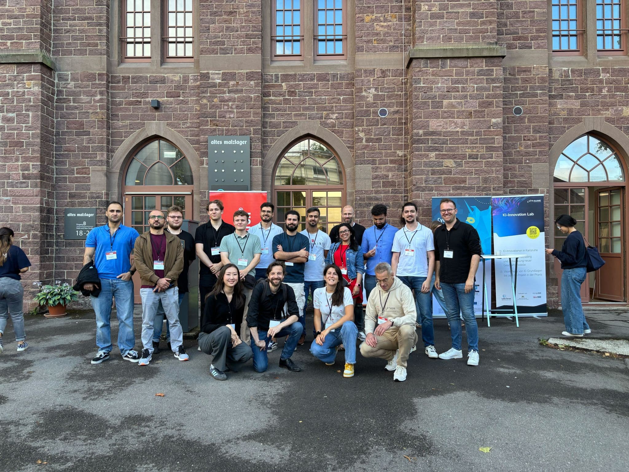 Group photo of about fifteen DynamoBot team members in front of a red-brick University of Bonn building.